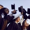 Diverse group of high school students throwing their graduation caps, angle from below